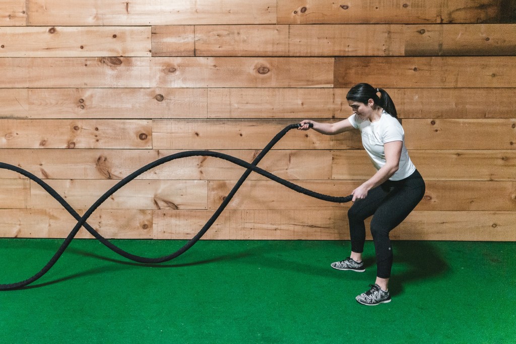 A young fitness instructor doing rope exercises 