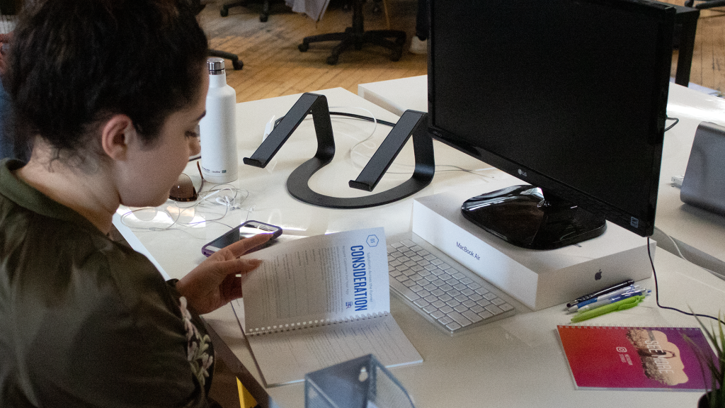 Female employee sitting at her office desk looking at a notebook.